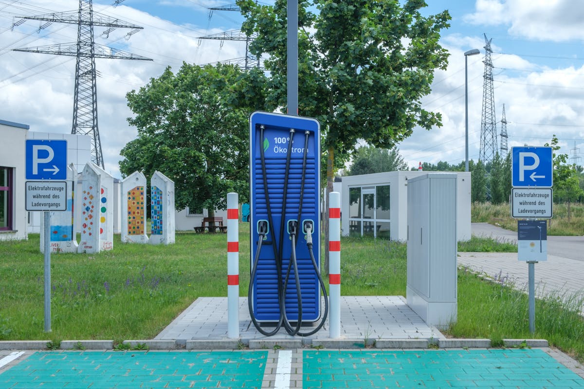 Borne de recharge rapide pour véhicules électriques devant des pylônes électriques haute tension